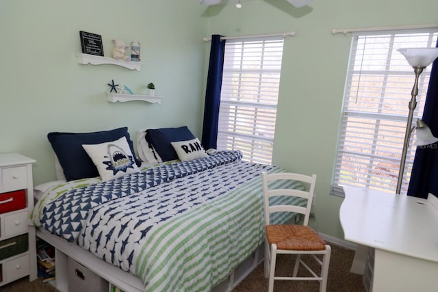 carpeted bedroom featuring multiple windows and ceiling fan