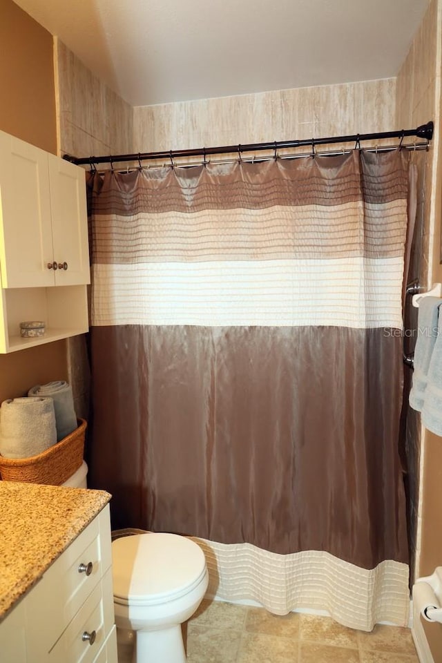 bathroom featuring tile patterned flooring, vanity, curtained shower, and toilet