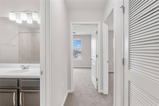 hallway with a sink, carpet, and baseboards
