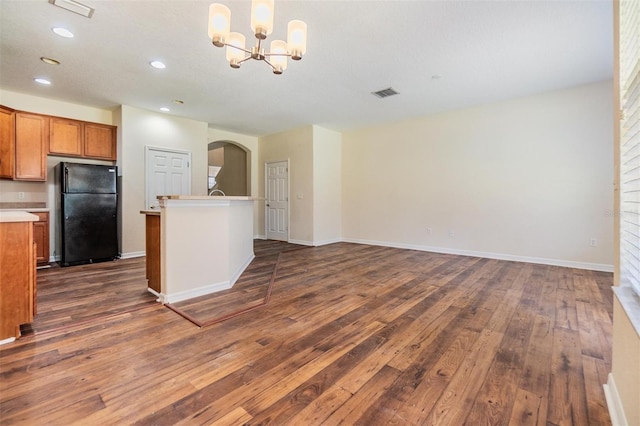 kitchen with black refrigerator, dark hardwood / wood-style floors, decorative light fixtures, and a chandelier