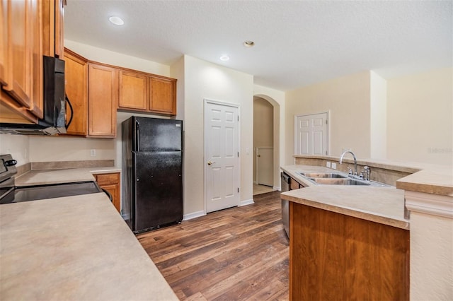 kitchen with electric range oven, sink, black fridge, dark wood-type flooring, and a textured ceiling