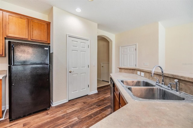 kitchen with black refrigerator, sink, stainless steel dishwasher, and dark hardwood / wood-style floors