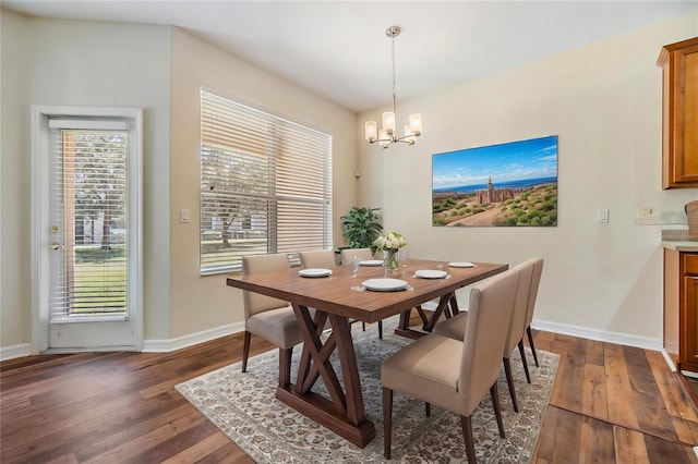 dining area featuring dark wood-type flooring, a healthy amount of sunlight, and a notable chandelier