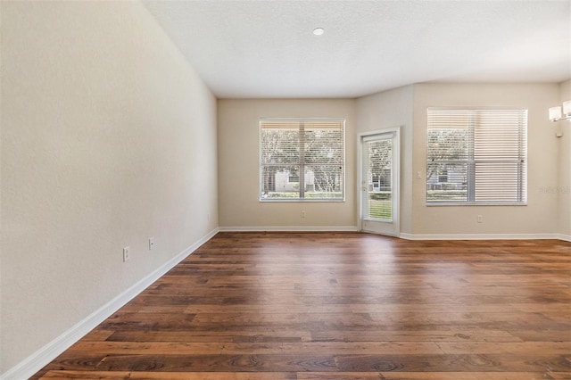 unfurnished room with dark hardwood / wood-style flooring and a textured ceiling