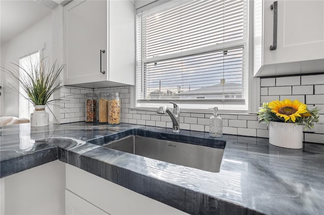 kitchen featuring sink, decorative backsplash, and white cabinets