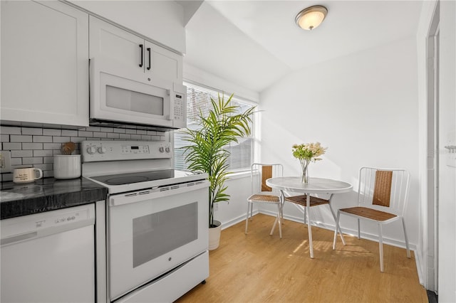 kitchen featuring vaulted ceiling, white appliances, light hardwood / wood-style floors, decorative backsplash, and white cabinets