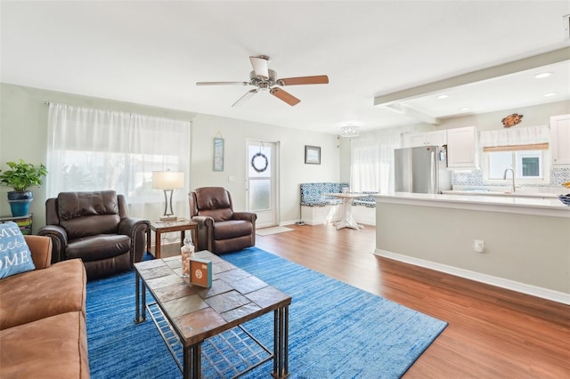 living room featuring beam ceiling, hardwood / wood-style floors, and ceiling fan