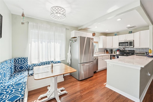 kitchen with white cabinetry, stainless steel appliances, tasteful backsplash, a wealth of natural light, and wood-type flooring