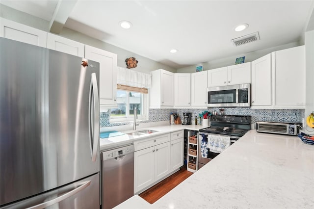 kitchen featuring appliances with stainless steel finishes, tasteful backsplash, sink, white cabinets, and dark wood-type flooring