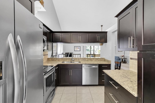 kitchen with light tile patterned flooring, appliances with stainless steel finishes, sink, decorative backsplash, and light stone countertops