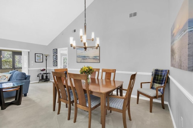 carpeted dining space featuring a chandelier and high vaulted ceiling