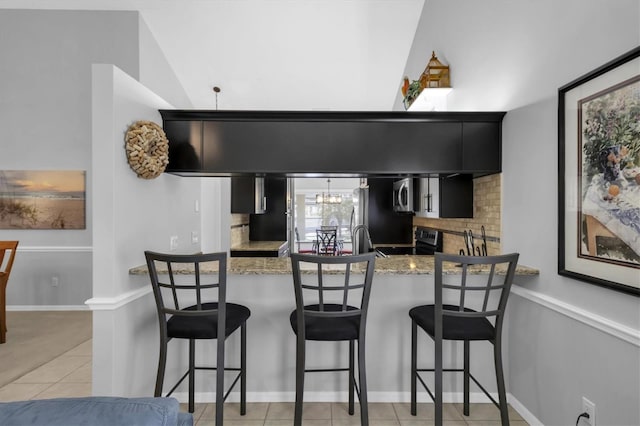 kitchen with light tile patterned flooring, sink, a chandelier, appliances with stainless steel finishes, and kitchen peninsula