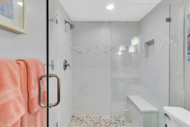 bathroom featuring toilet and a shower with shower door