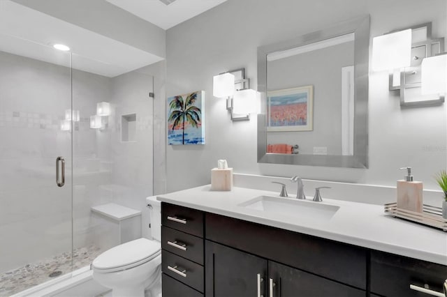 bathroom with a shower with door, vanity, and toilet