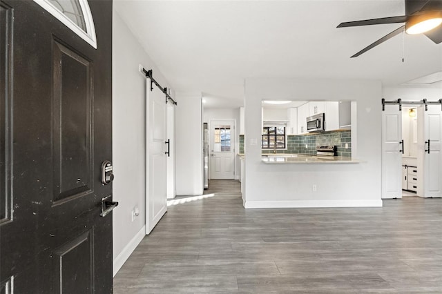 entryway featuring hardwood / wood-style flooring, ceiling fan, and a barn door