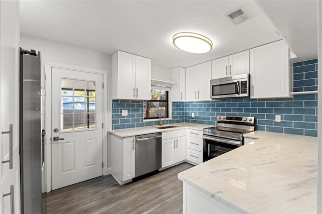 kitchen with white cabinetry, sink, light stone countertops, and appliances with stainless steel finishes