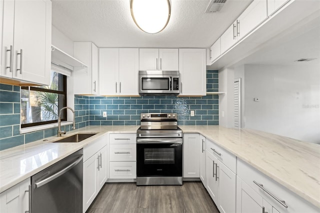 kitchen featuring appliances with stainless steel finishes, white cabinetry, sink, light stone countertops, and dark wood-type flooring