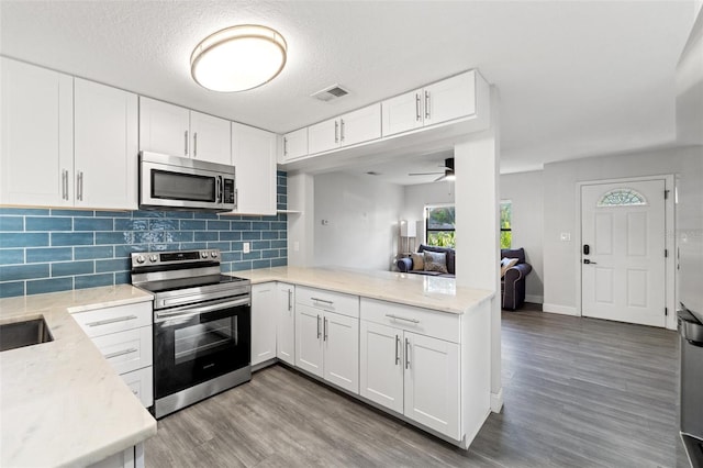 kitchen featuring tasteful backsplash, stainless steel appliances, light hardwood / wood-style flooring, and white cabinets