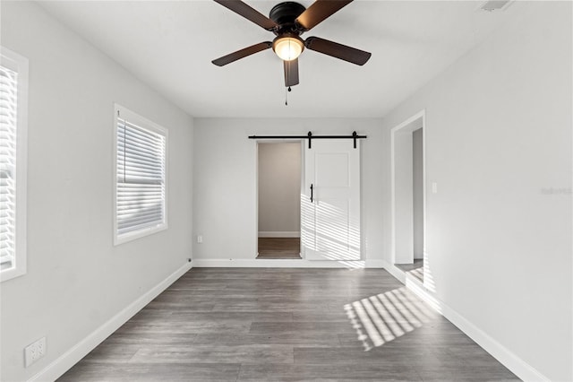 unfurnished bedroom featuring ceiling fan, a barn door, and hardwood / wood-style floors