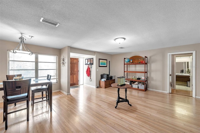 dining area with a textured ceiling and light wood-type flooring