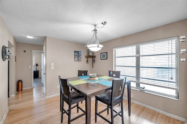 dining space with a textured ceiling and light hardwood / wood-style flooring