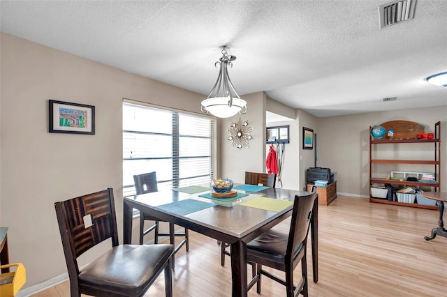 dining space with a textured ceiling and light wood-type flooring