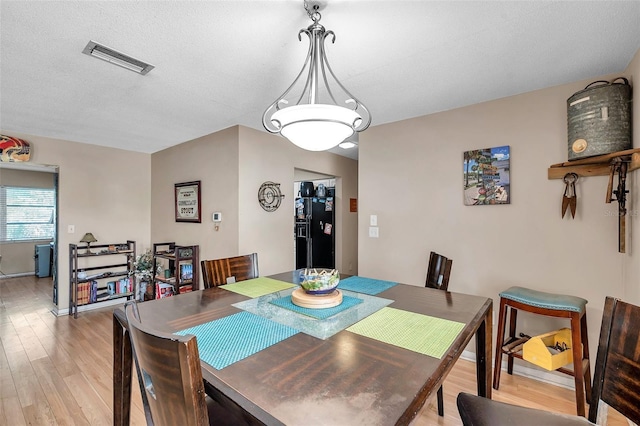 dining space featuring a textured ceiling and light hardwood / wood-style flooring