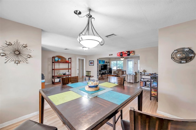 dining space featuring light hardwood / wood-style flooring and a textured ceiling