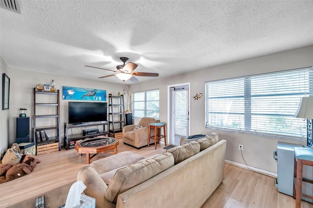 living room with ceiling fan, light hardwood / wood-style flooring, and a textured ceiling