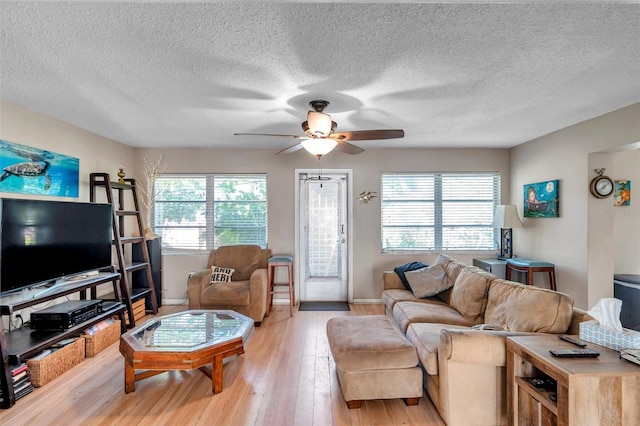 living room featuring ceiling fan, plenty of natural light, light hardwood / wood-style floors, and a textured ceiling