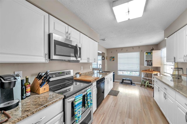 kitchen featuring stainless steel appliances, white cabinets, light stone counters, and light hardwood / wood-style floors