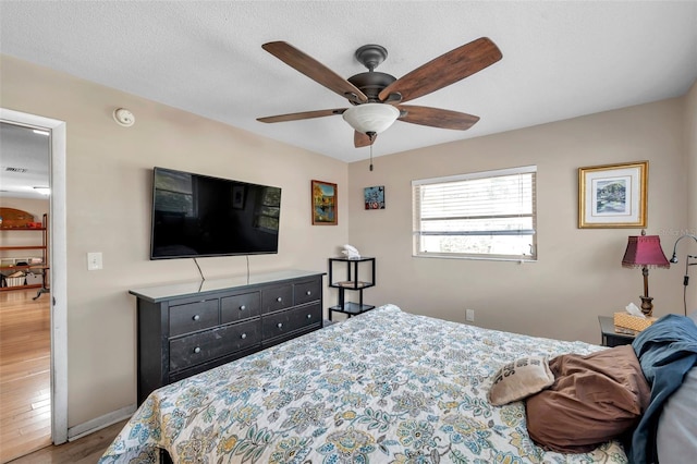 bedroom featuring hardwood / wood-style flooring, ceiling fan, and a textured ceiling