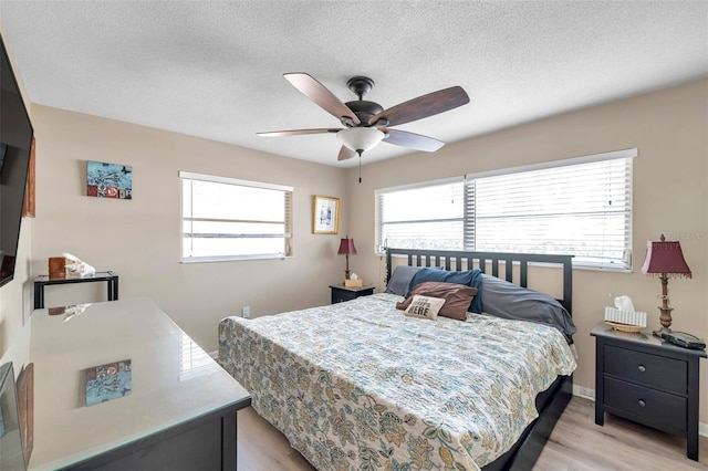 bedroom featuring ceiling fan, light hardwood / wood-style floors, and a textured ceiling