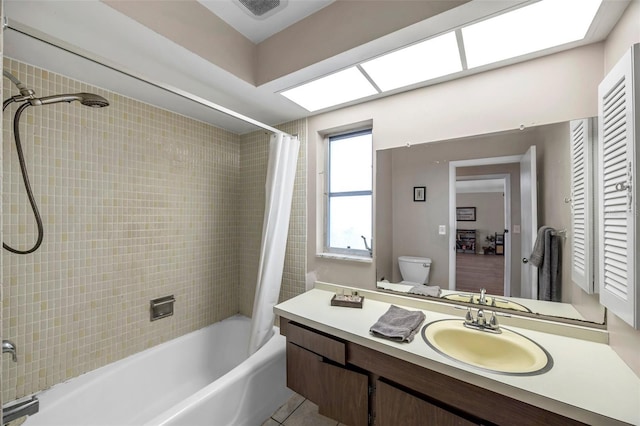 full bathroom featuring toilet, a skylight, vanity, shower / bathtub combination with curtain, and tile patterned flooring