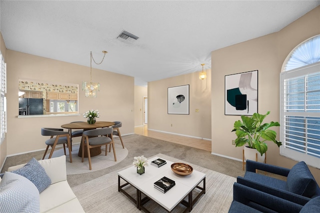 carpeted living room featuring a notable chandelier, a textured ceiling, and a wealth of natural light