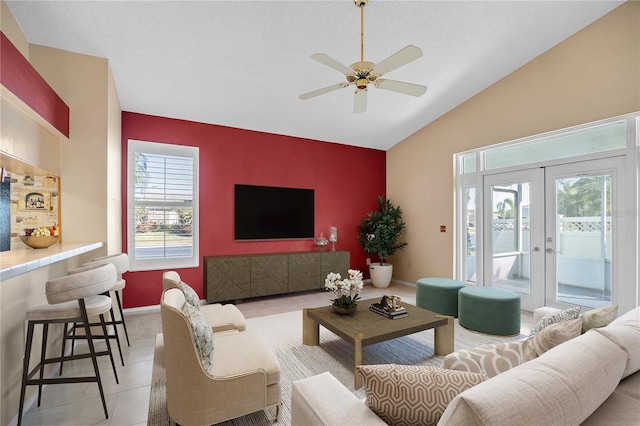 tiled living room with lofted ceiling, a textured ceiling, french doors, and ceiling fan