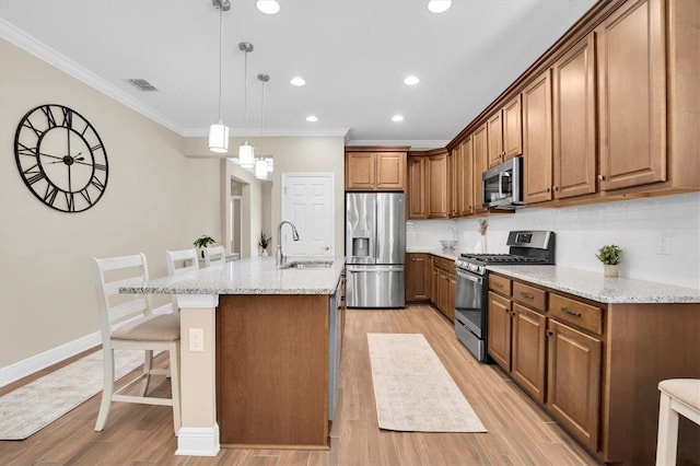 kitchen with pendant lighting, sink, a kitchen island with sink, light stone counters, and stainless steel appliances