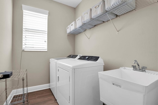 washroom with dark hardwood / wood-style floors, washer and clothes dryer, and sink