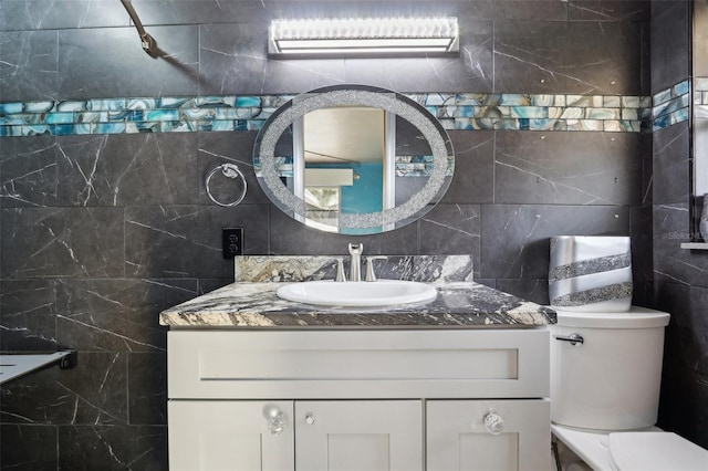 bathroom with vanity, toilet, and tile walls