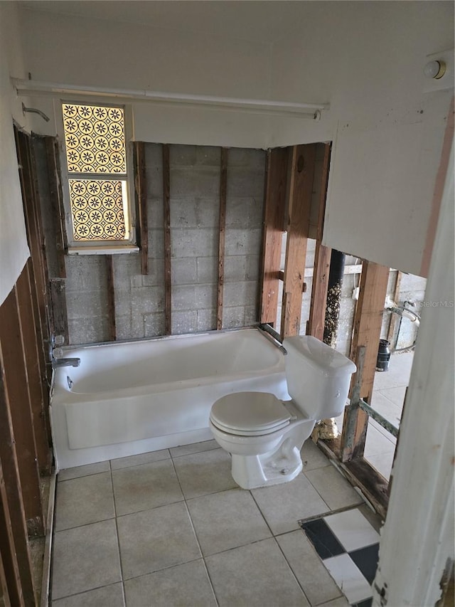 bathroom featuring tile patterned flooring, a tub, and toilet