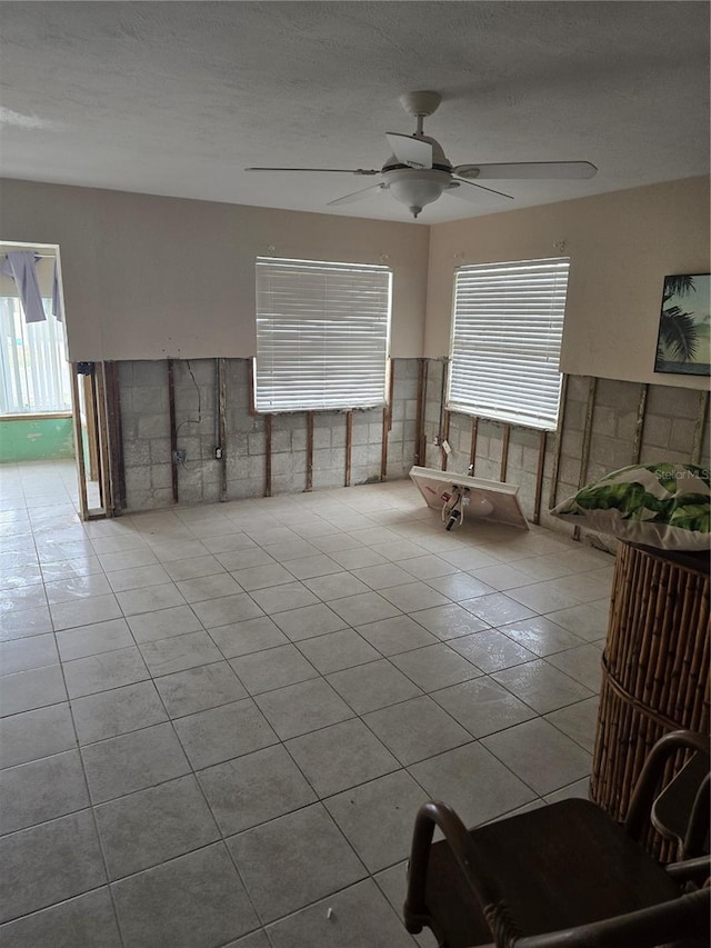 living room with ceiling fan, light tile patterned floors, and a textured ceiling