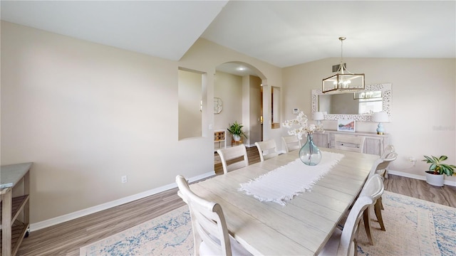 dining area featuring lofted ceiling, a notable chandelier, and light wood-type flooring