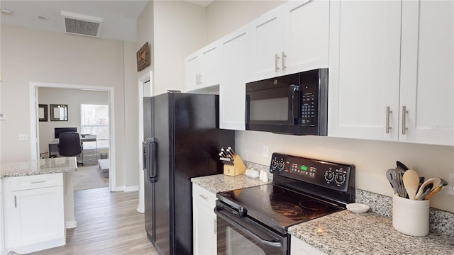 kitchen featuring light stone countertops, white cabinets, light hardwood / wood-style floors, and black appliances