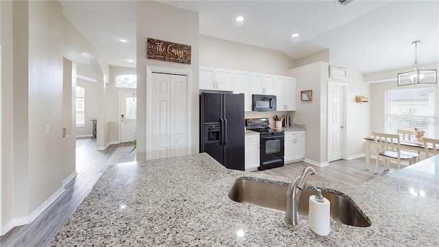 kitchen with sink, white cabinets, black appliances, light stone countertops, and light wood-type flooring