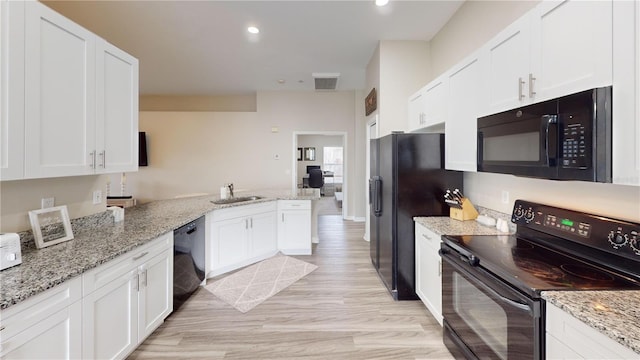 kitchen with white cabinetry, light stone countertops, kitchen peninsula, and black appliances