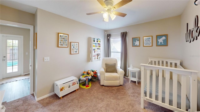 bedroom featuring ceiling fan, light carpet, and a crib