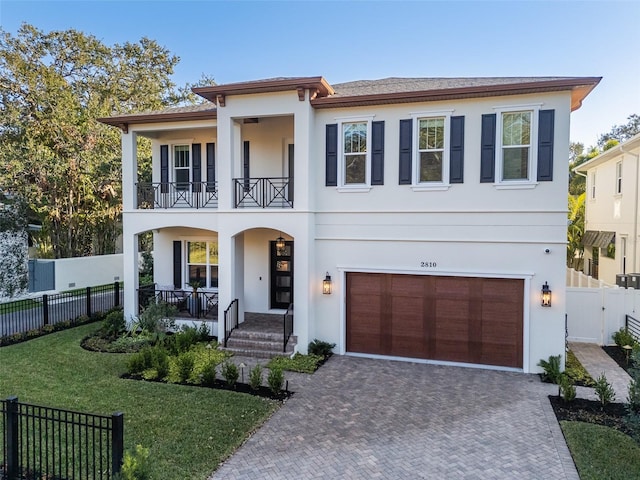 view of front of house featuring a garage, a balcony, a front yard, and covered porch