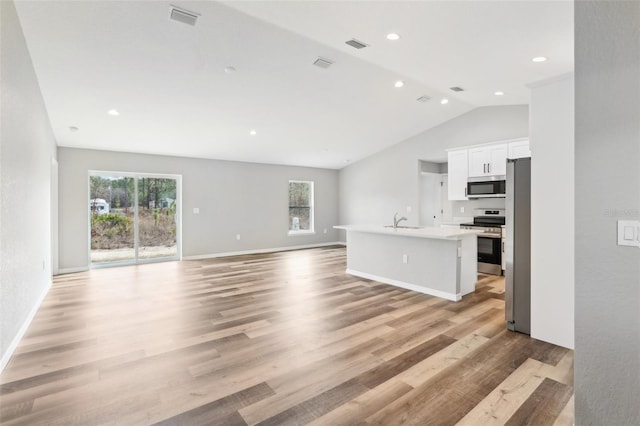 unfurnished living room featuring lofted ceiling, sink, and light hardwood / wood-style flooring