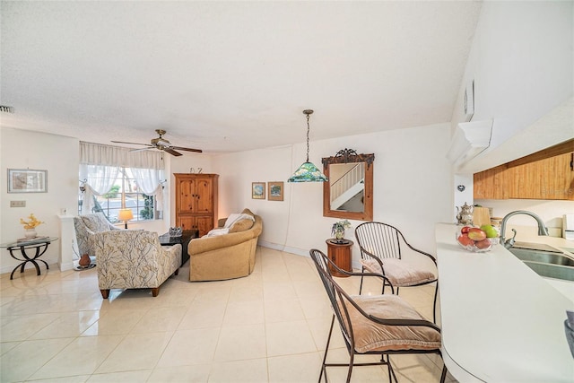 living room featuring ceiling fan, sink, and light tile patterned floors