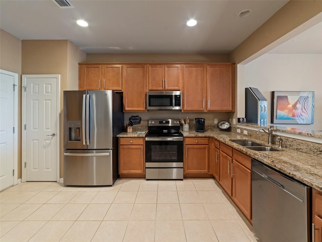 kitchen with light stone countertops, appliances with stainless steel finishes, sink, and light tile patterned flooring